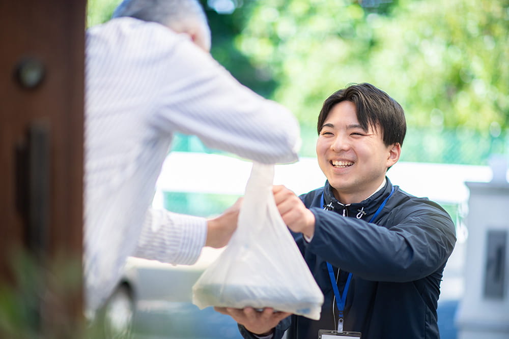 宅配弁当を高齢者に手渡しで配達するスタッフ